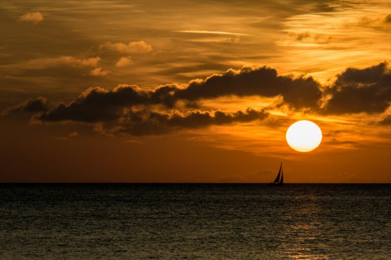 silhouette of sailboat on sea during golden hour